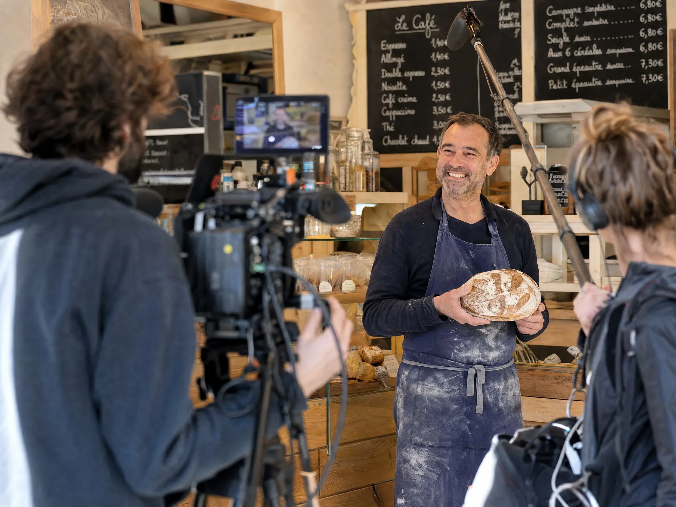 Tournage d'un spot dans une boulangerie : la boulangère au comptoir, cadrée sur l'écran de la caméra